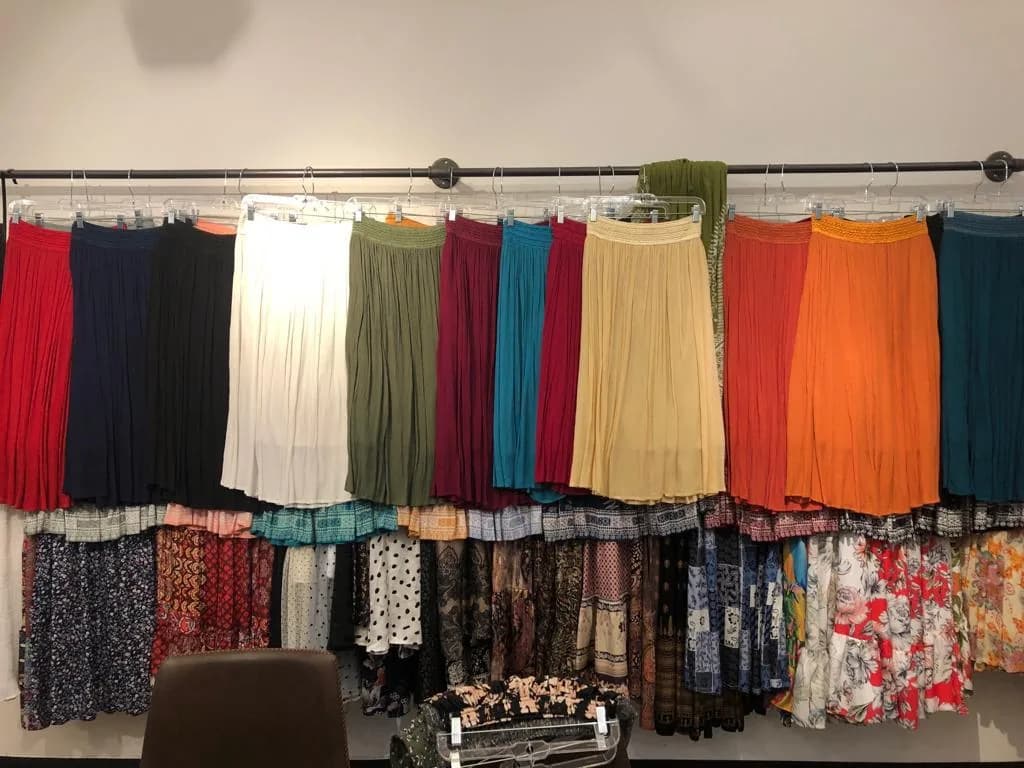 Rail of crinkle pleated midi skirts in a range of colours, with printed skirts below