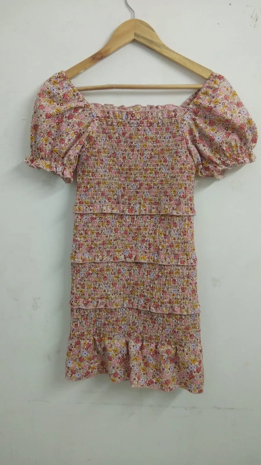 Front view of a pink floral ditsy floral smocked puff-sleeve mini dress on a hanger