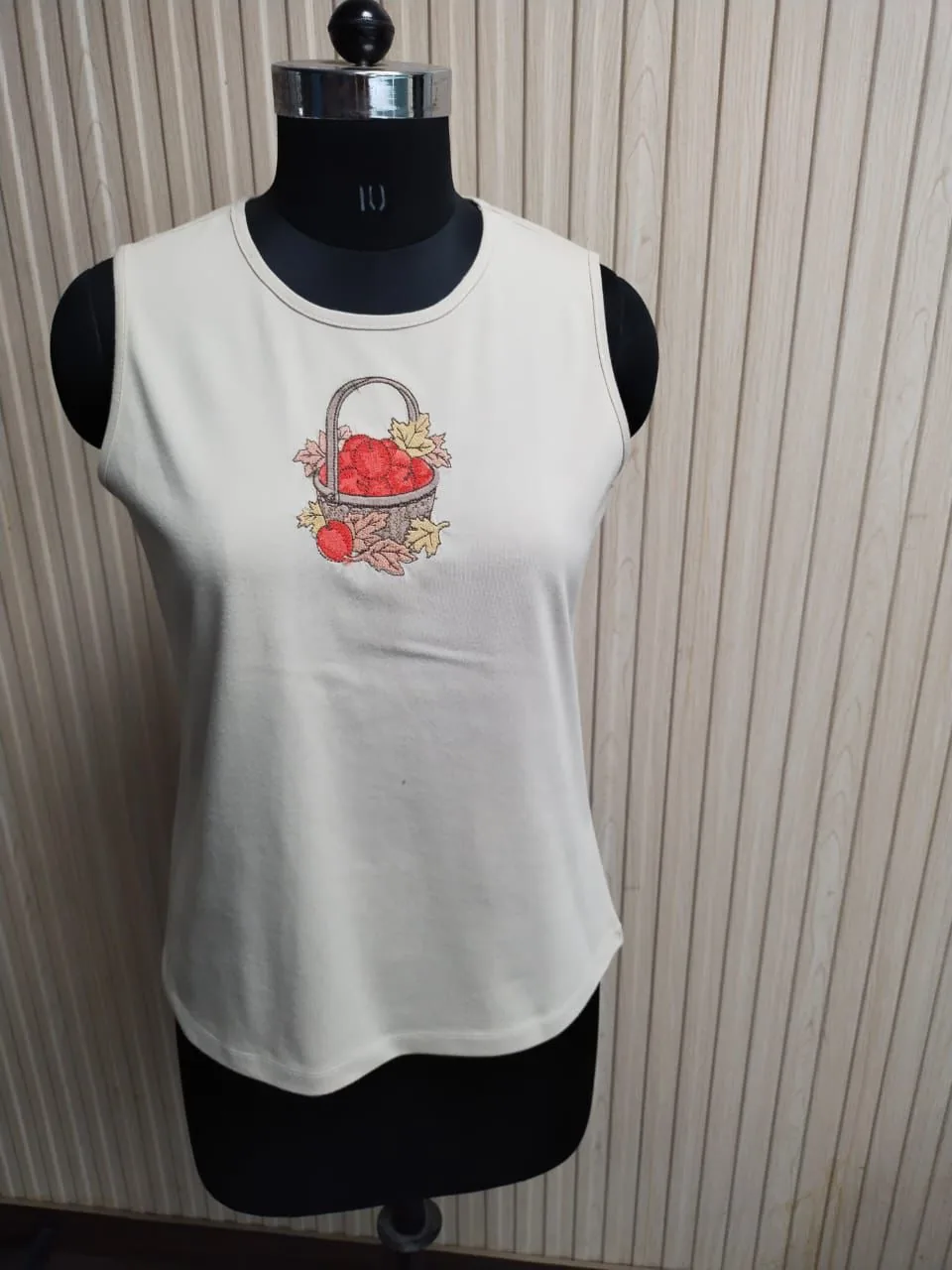 Front view of a white embroidered jersey tank top on a dress form