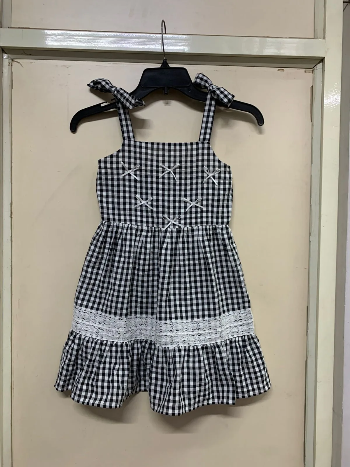 Front view of a navy gingham gingham tie-strap smocked mini dress on a hanger