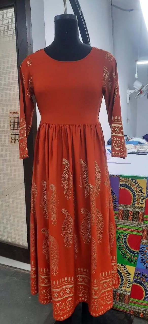 Front view of a rust orange gold-foil paisley long-sleeve maxi dress on a dress form