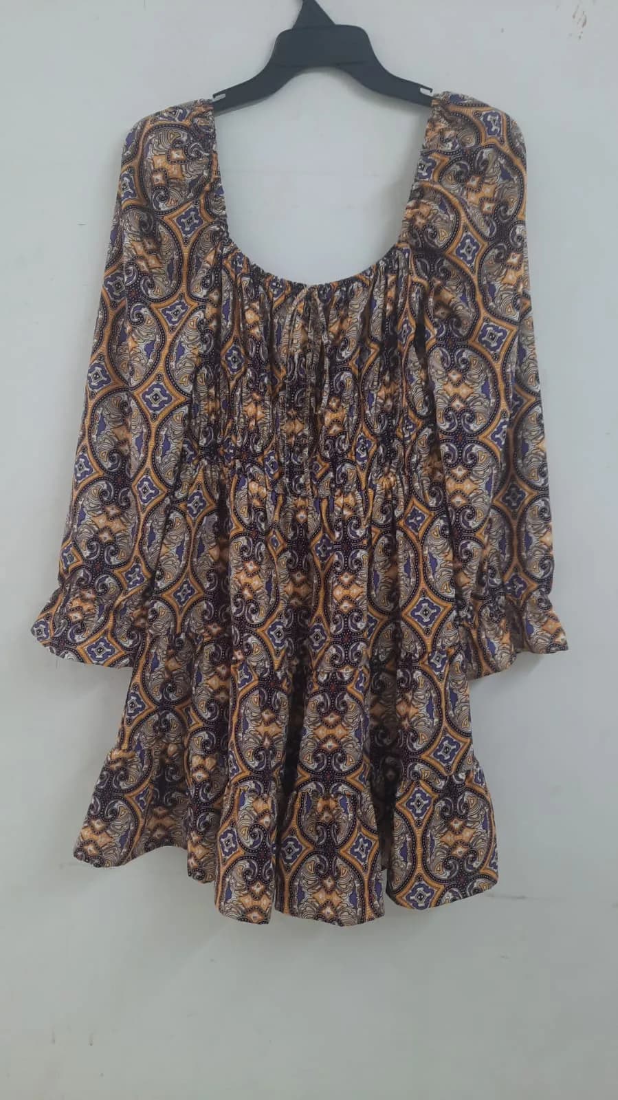 Front view of a purple and mustard medallion-print long-sleeve smocked mini dress on a hanger