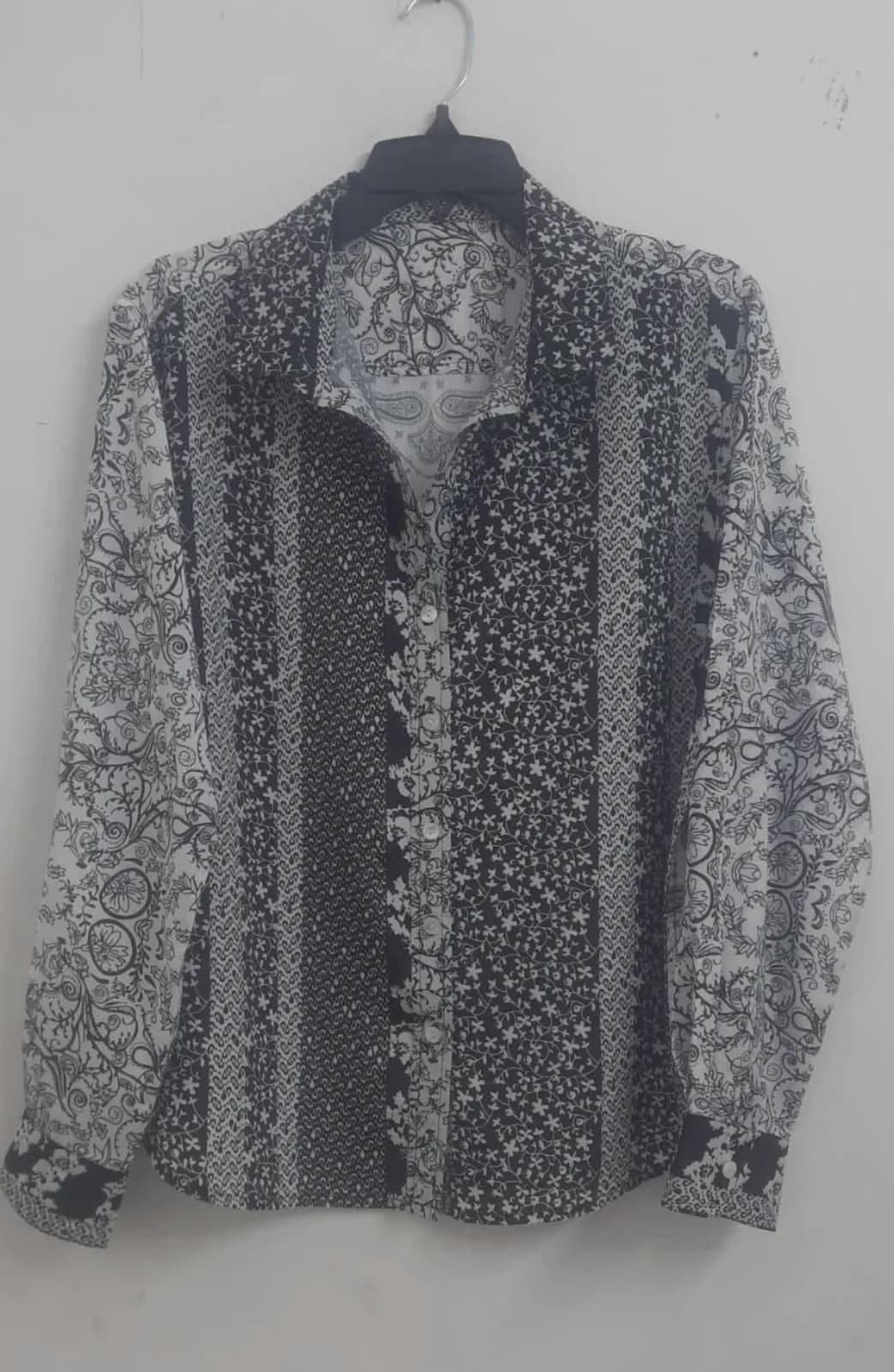 Front view of a black and white patchwork-print long-sleeve shirt on a hanger