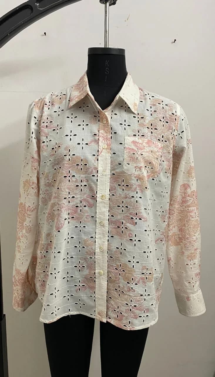 Front view of a cream and pink printed eyelet button-down shirt on a dress form