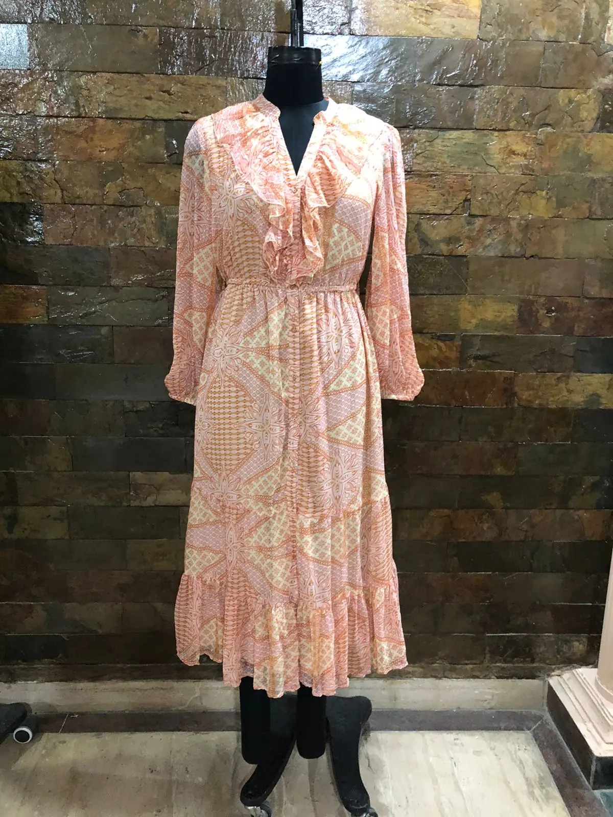 Front view of a peach printed ruffle-neck long-sleeve maxi dress on a dress form