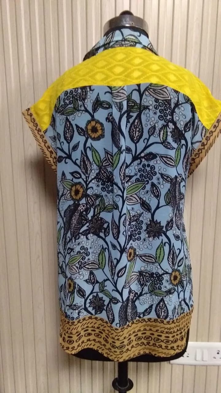 Back view of a blue and yellow printed shirt with lace yoke on a dress form