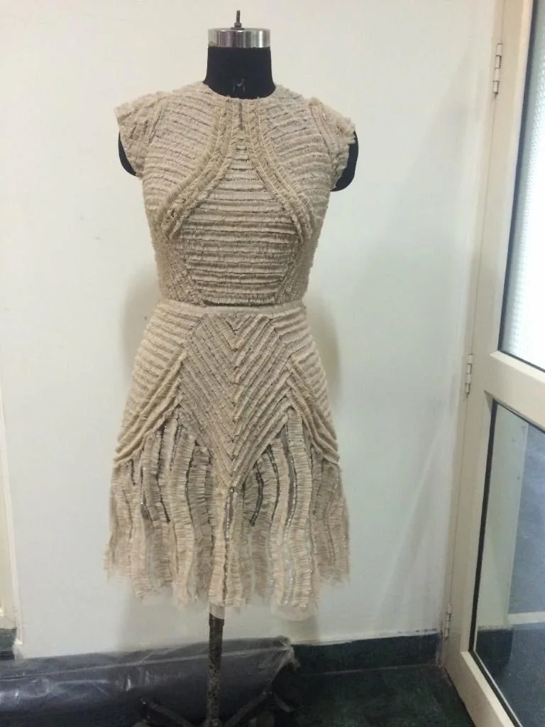 Front view of a beige textured sleeveless fit-and-flare dress on a dress form