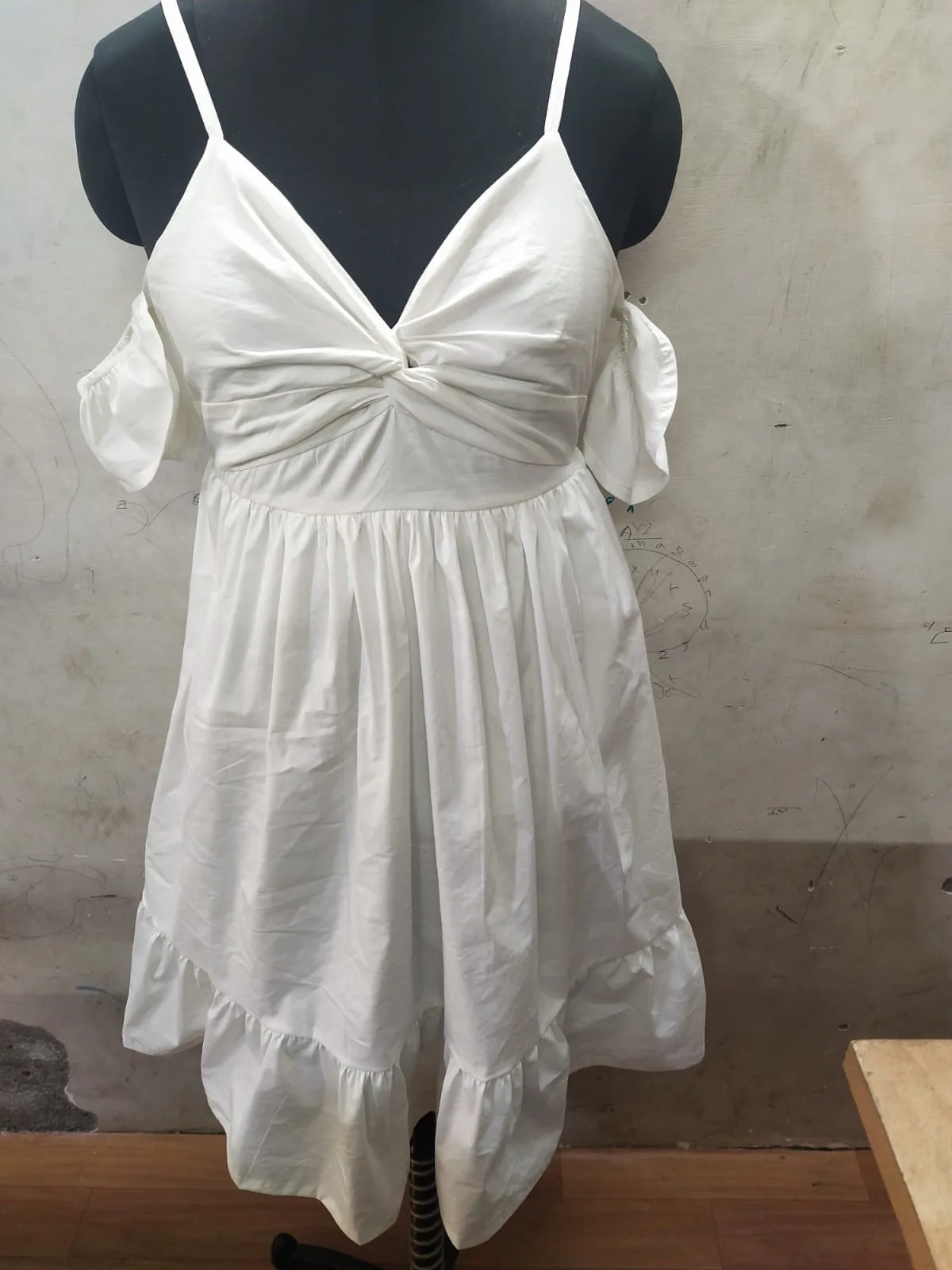 Front view of a white twist-front cold-shoulder mini dress on a dress form