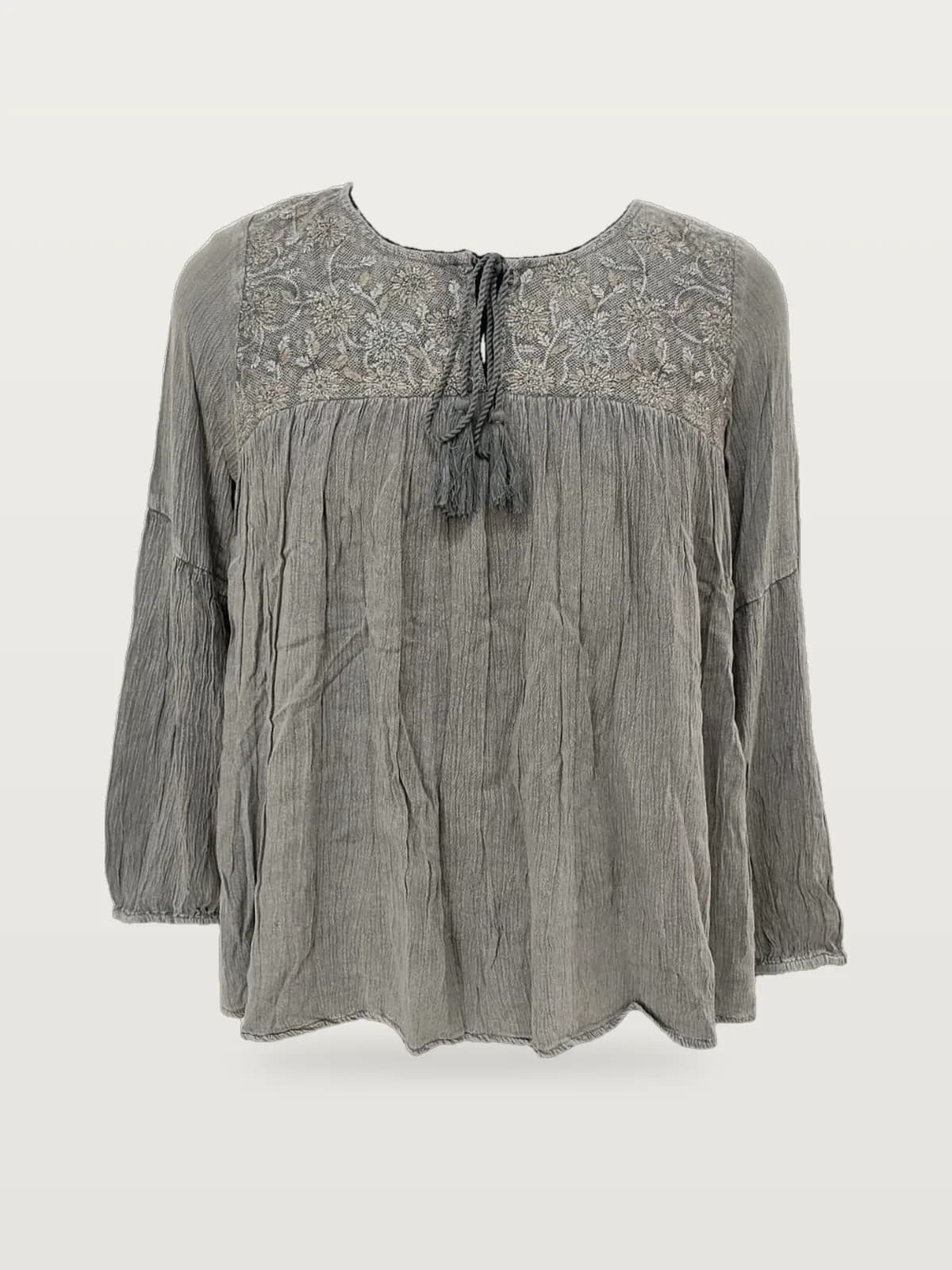 Front view of a grey crinkle embroidered-yoke tie-neck blouse on a dress form