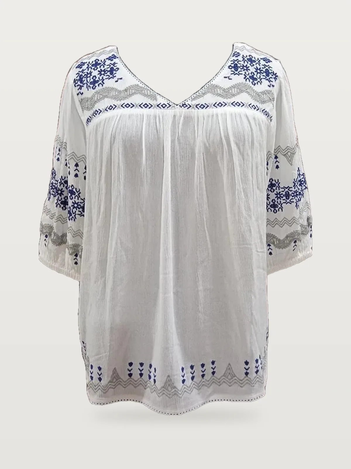 Front view of a white and blue cross-stitch embroidered peasant blouse on a dress form