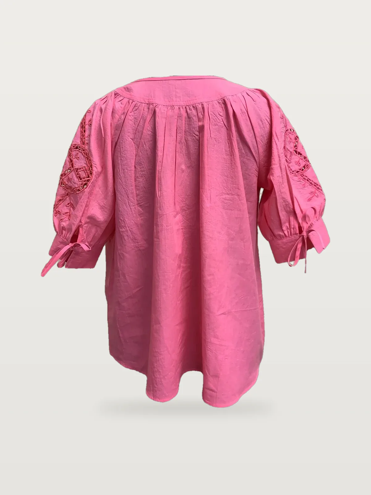 Back view of a pink cutwork-sleeve blouse with tie cuffs on a dress form