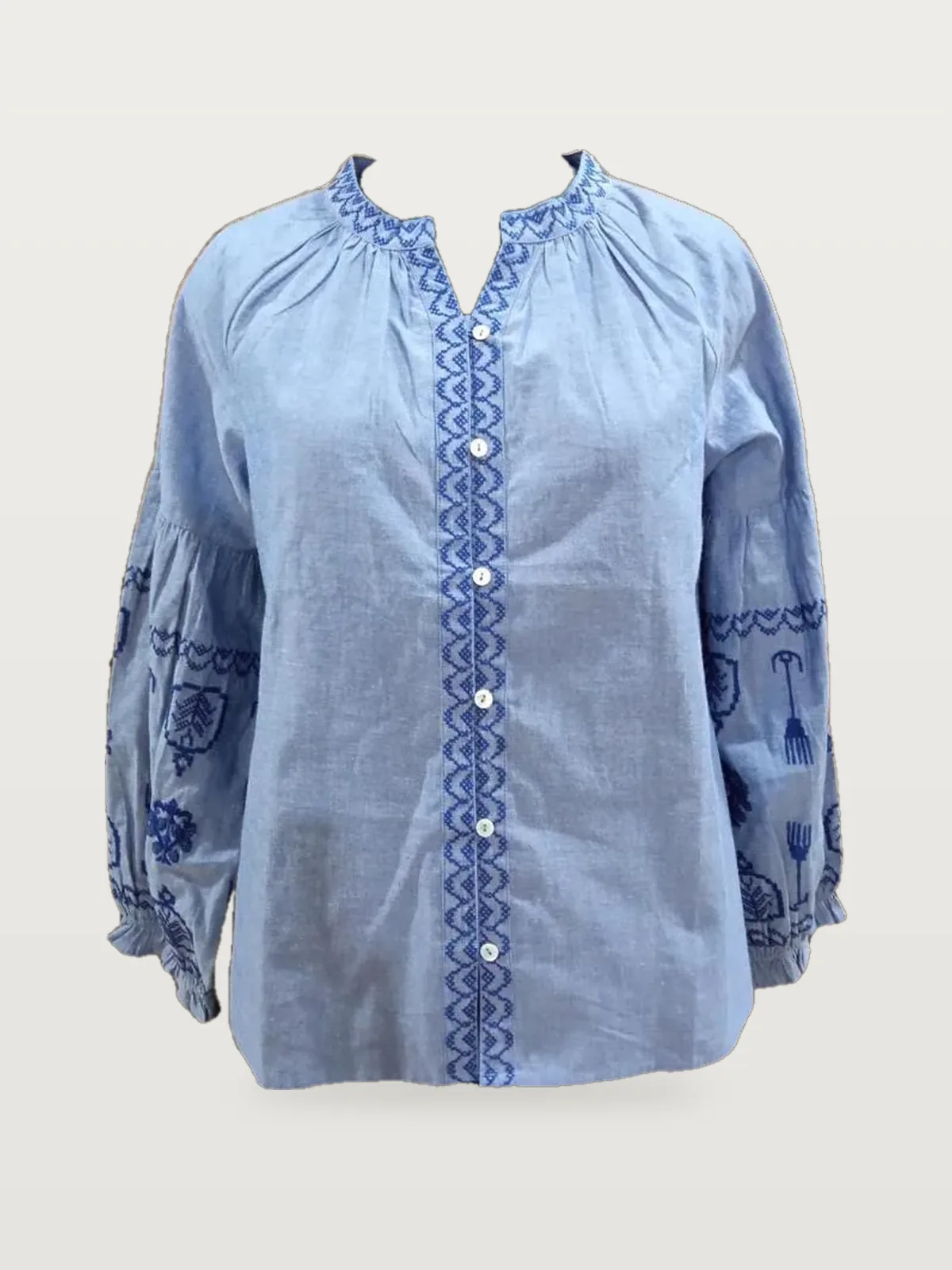 Front view of a light blue embroidered chambray blouse on a dress form