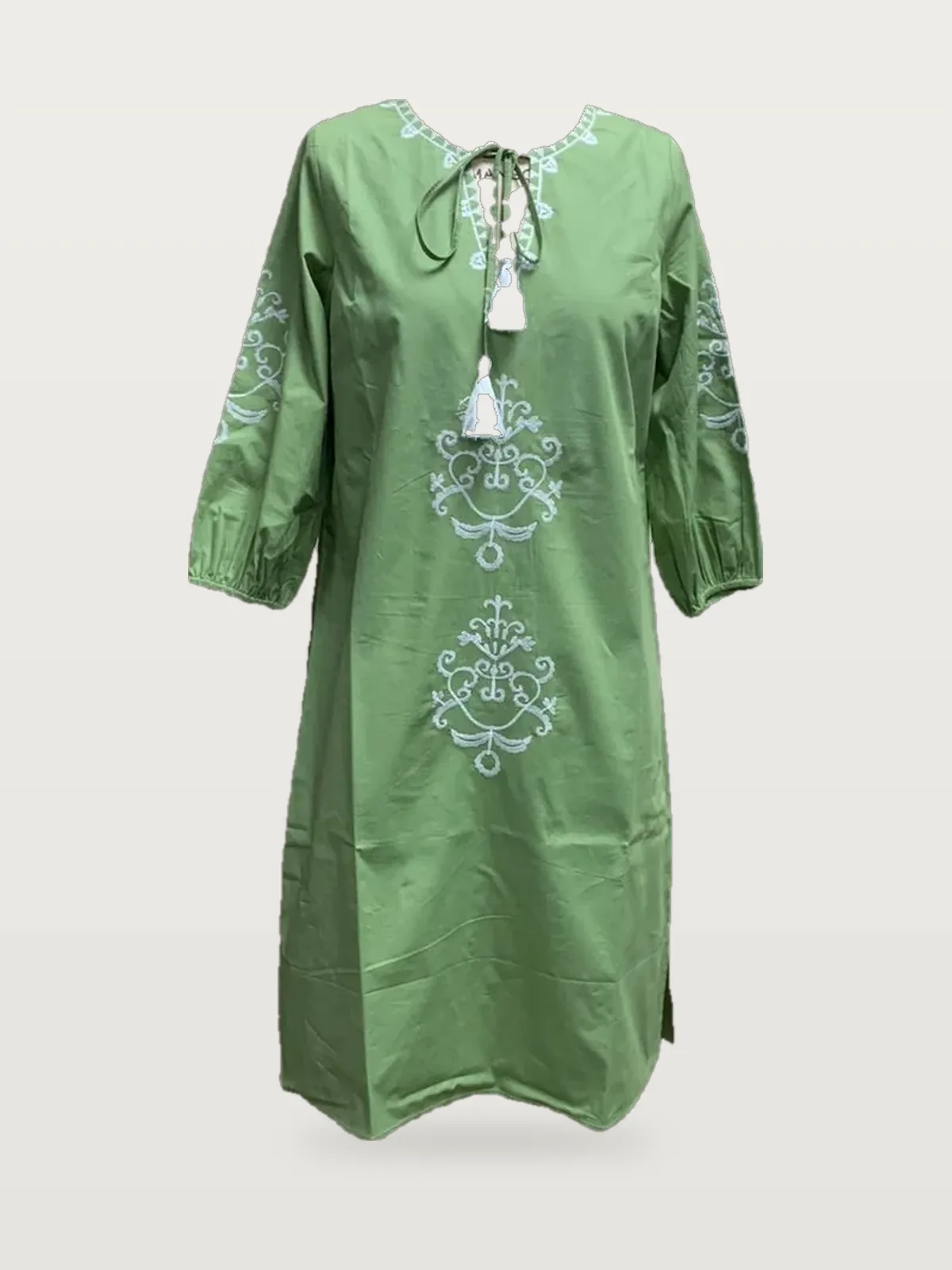 Front view of a green embroidered tunic with tassel tie-neck on a dress form