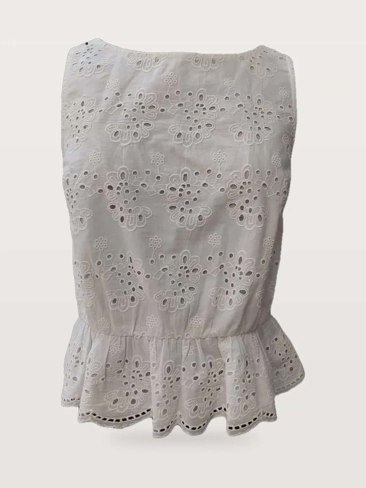 Front view of a white eyelet sleeveless peplum top on a dress form