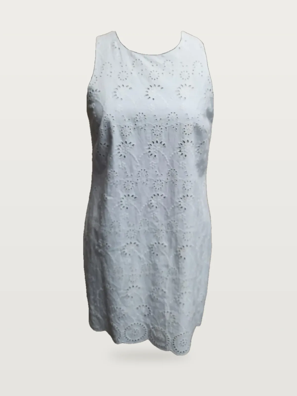 Front view of a white eyelet sleeveless shift dress on a dress form