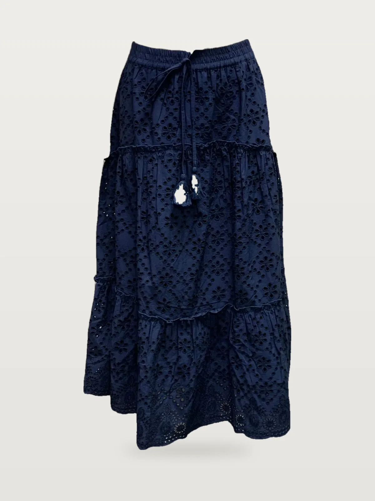 Front view of a navy eyelet tiered maxi skirt with tassel drawstring on a dress form