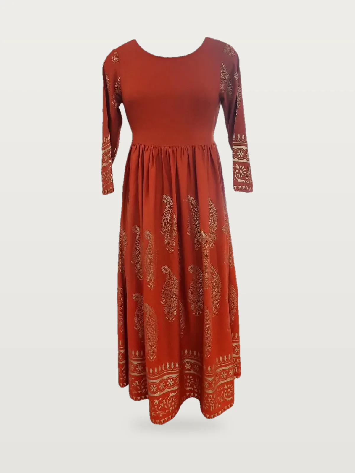 Front view of a rust orange gold-foil paisley long-sleeve maxi dress on a dress form