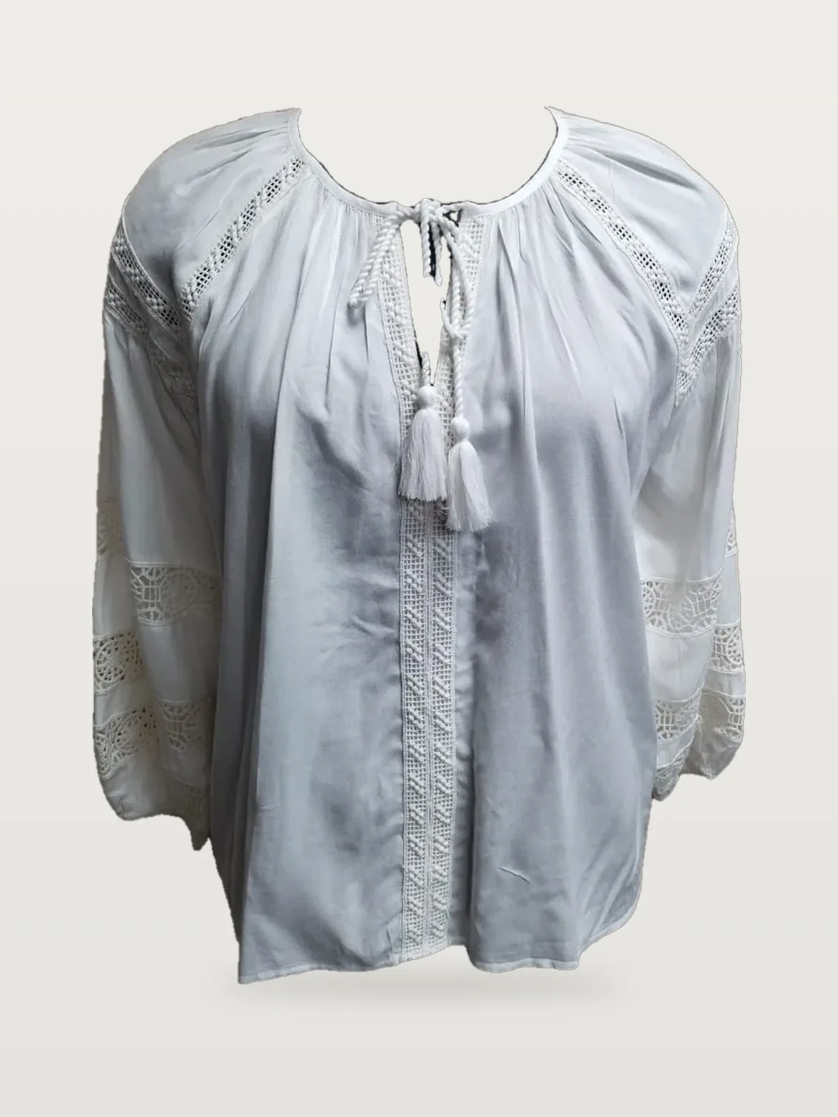 Front view of a white lace-insertion peasant blouse with tassels on a dress form