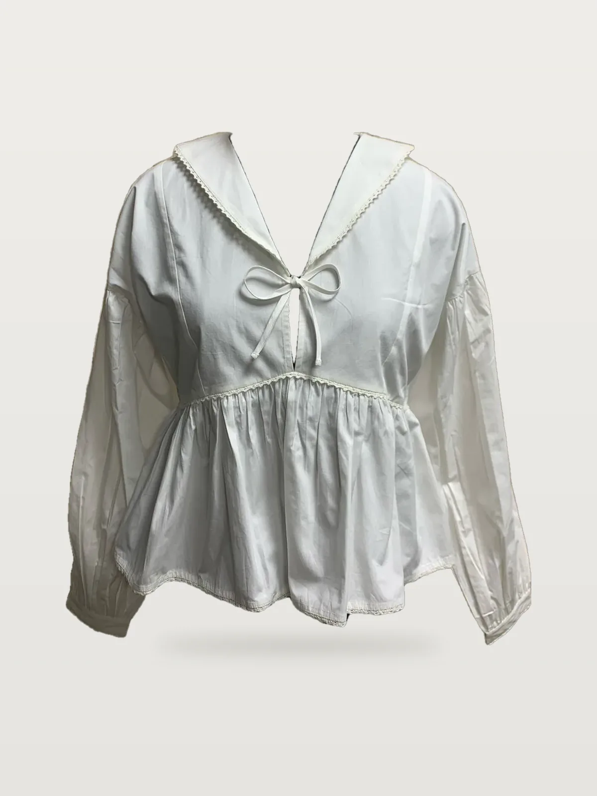 Front view of a white sailor-collar peplum blouse on a dress form
