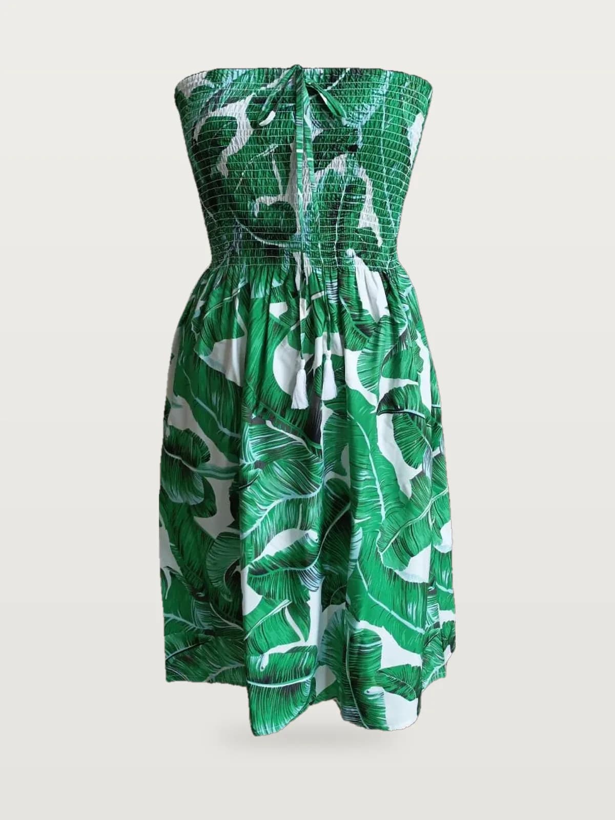 Front view of a green palm print smocked strapless mini sundress on a dress form