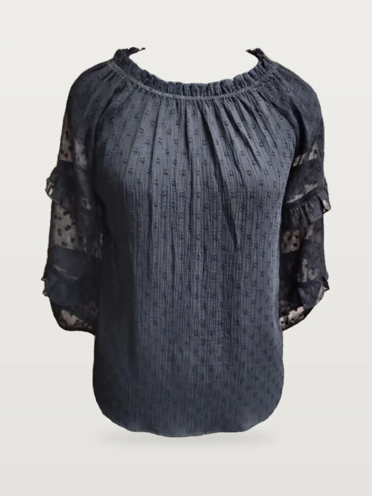 Front view of a black swiss-dot blouse with sheer lace sleeves on a dress form