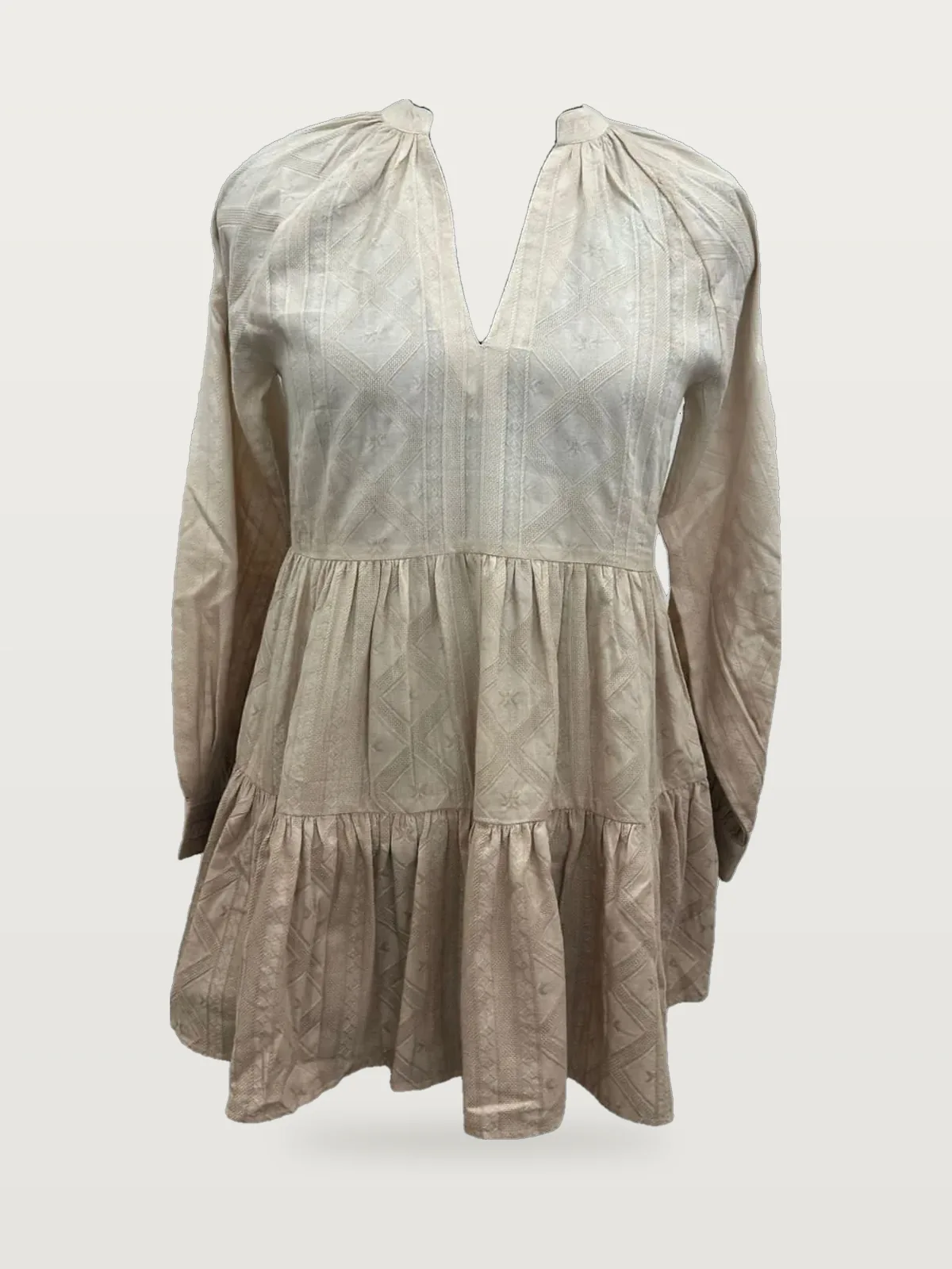 Front view of a beige textured tiered tunic top on a dress form