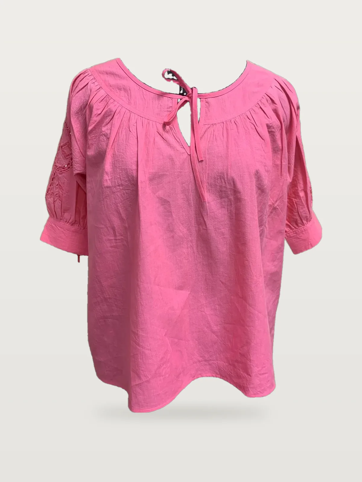 Front view of a pink tie-neck smocked-yoke peasant blouse on a dress form