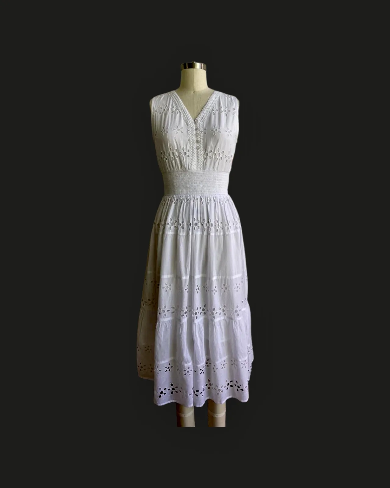 Front view of a white eyelet V-neck tiered midi dress on a dress form