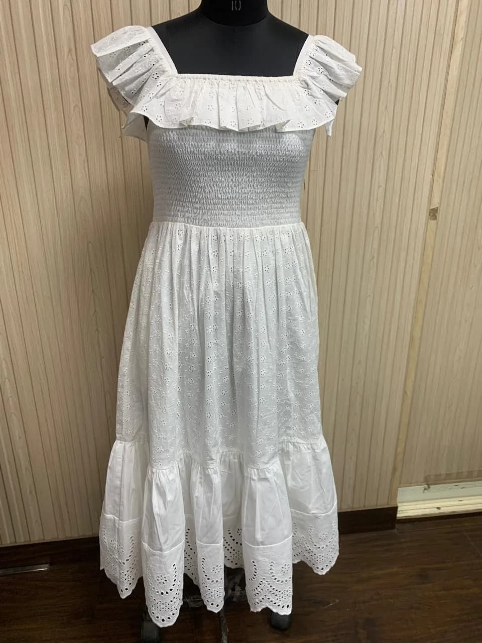 Front view of a white smocked ruffle-strap midi dress with eyelet hem on a dress form